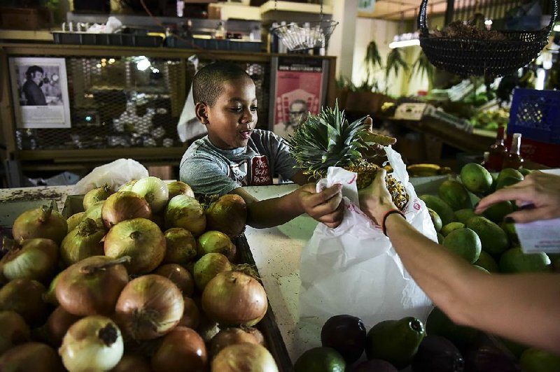 Yoniel Santana works at his grandmother’s produce stand last week at La Placita de Santurce farmers market which sells mostly locally grown produce in San Juan, Puerto Rico. 