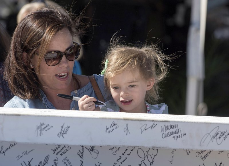 Jenessa Bailey of Fayetteville helps her daughter, Maye, 3, sign a steel beam Wednesday at the Arkansas Children’s Hospital Northwest’s topping-out ceremony. The beam represents the highest point on the skeleton of the structure as it gets closer to its early 2018 opening. The hospital is at the corner of 56th Street and Watkins Avenue in Springdale. 