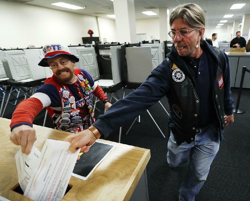 Iowans John Olsen (left) and Mark Cooper compete Thursday to be the first to drop a ballot into the box in Des Moines on the first day of early voting in the state. 