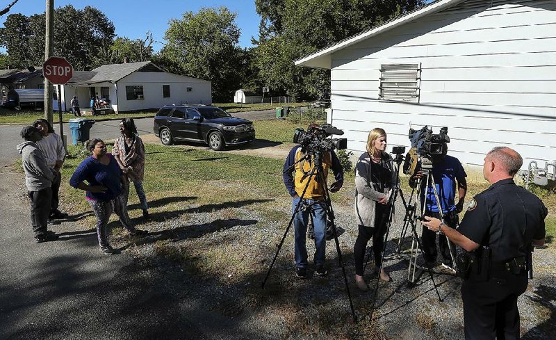 Neighbors gather Thursday at West 26th and Elm streets as Little Rock police spokesman Lt. Steve McClanahan (right) briefs reporters on a fatal shooting at the intersection late Wednesday.