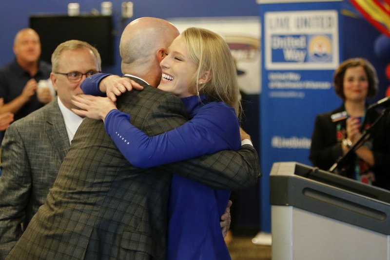 Jeff Long (left), athletic director at the University of Arkansas, watches Thursday as Sandi Morris (right), Olympic silver medalist and former university athlete, receives a hug from Tim Marrin, external relations with Procter & Gamble, after Morris spoke at the kickoff event for the 2017 United Way of Northwest Arkansas campaign at Arvest Ballpark in Springdale.