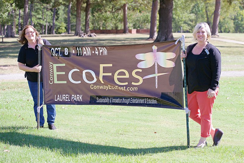 Festival co-coordinators Debbie Plopper, left, and Treci Buchanan stand with the EcoFest banner in Laurel Park in Conway, where the eighth annual event will be held Saturday. In addition to popular activities such as the 
recycled-materials car derby, a new attraction this year is the Enviro-Maze, in which contestants can win prizes. More information is available at conwayecofest.com.