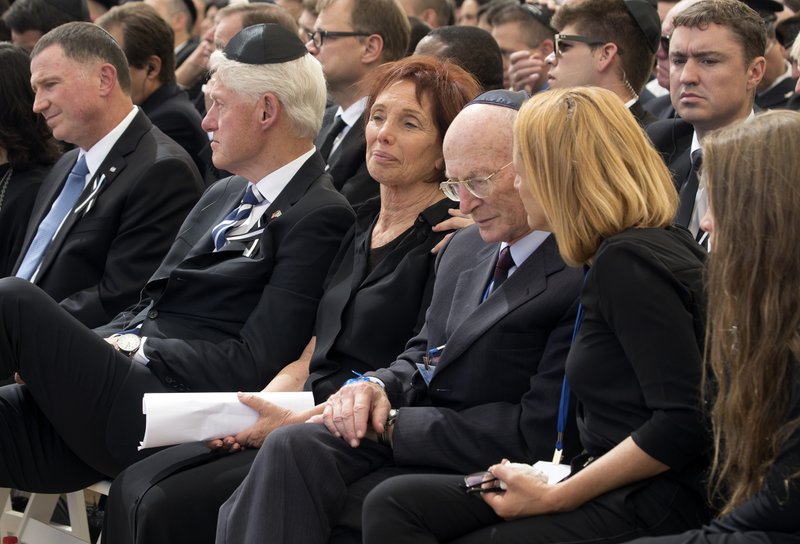 Former U.S. President Bill Clinton, second left, sits next to Dr. Tsvia Walden, known as "Tsiki," the daughter of former Israeli President Shimon Peres during his funeral at Mt. Herzl Military Cemetery in Jerusalem, Friday, Sept. 30, 2016. Peres was laid to rest on Friday in a ceremony attended by thousands of admirers and dozens of international dignitaries — in a final tribute to a man who personified the history of Israel during a remarkable seven-decade political career and who came to be seen by many as a visionary and symbol of hopes of Mideast peace. (Stephen Crowley/Pool Photo via AP)
