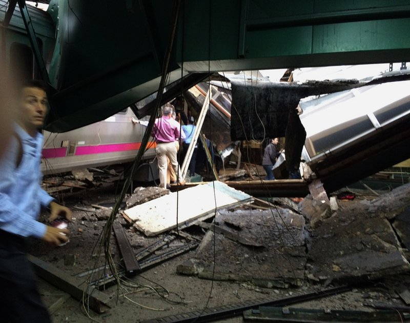 In a photo provided by William Sun, people examine the wreckage of a New Jersey Transit commuter train that crashed into the train station during the morning rush hour in Hoboken,, N.J., Thursday, Sept. 29, 2016. The crash caused an unknown number of injuries and witnesses reported seeing one woman trapped under concrete and many people bleeding. (William Sun via AP)
