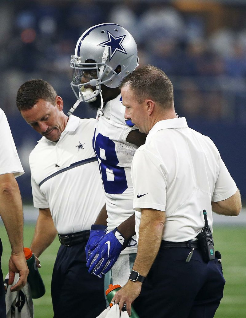 Dallas Cowboys wide receiver Dez Bryant (center) is helped off the field during the first half of Sunday’s game against the Chicago Bears in Arlington, Texas. Bryant, who did not practice all week, is listed as questionable after suffering a hairline fracture above his right knee.