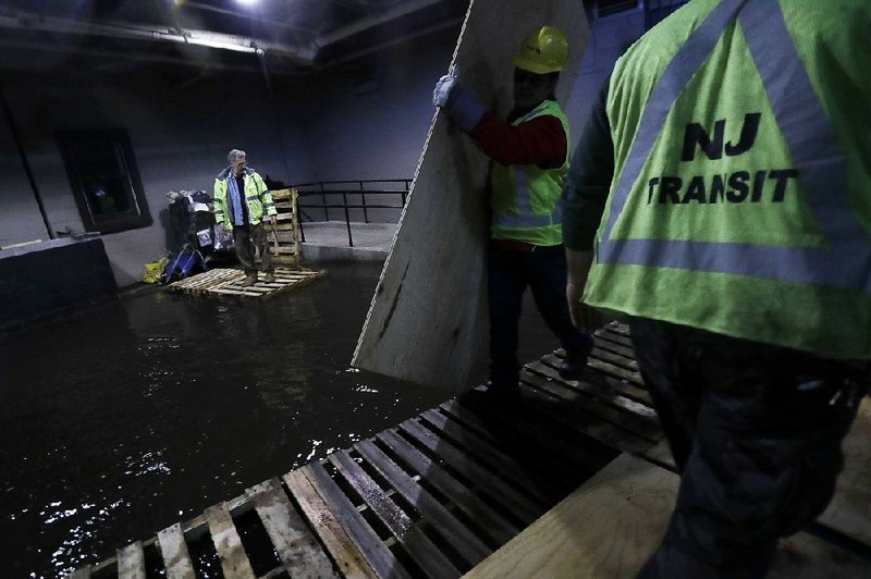 Transit workers put down pallets and boards as walkways Friday in a flooded hallway near the site in the Hoboken, N.J., station where a commuter train crashed Thursday.