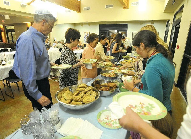 Temple Shalom members fill their plates as they break their fast following the end of Yom Kippur last year at Temple Shalom of Northwest Arkansas in Fayetteville. The practice of fasting goes back to the biblical verse in Leviticus 26:27, which instructs the people of Israel to “afflict their souls” on Yom Kippur. Some feel that refraining from food or luxuries helps them better focus on the meaning of the day.