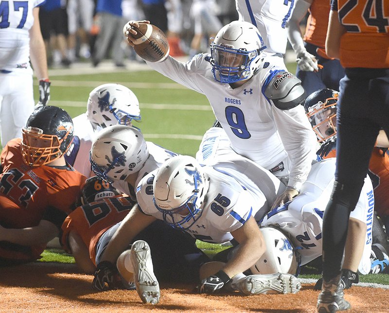 Rogers High quarterback Max Horton (9) pushes into the end zone for a touchdown Friday during the Mounties' game against Heritage in Rogers.