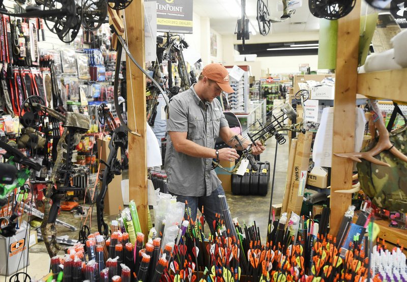 Jason Curlee of Fayetteville takes a look at the bows for sale Saturday at Southtown Sporting Goods in Springdale as he gets ready to go hunting for the weekend.