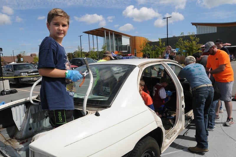 Dominic Vick, 8, helps take a car apart Saturday at the third annual Tinkerfest at the Scott Family Amazeum in Bentonville. Members of the area British Iron Club helped kids take parts off of the car.