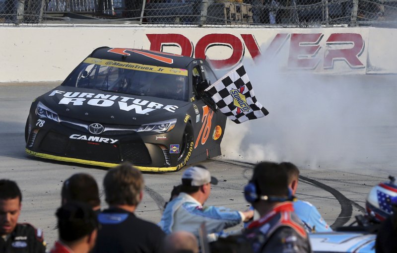 Martin Truex Jr., (78) holds the checkered flag as he does a burnout after winning a NASCAR Sprint Cup Series auto race, Sunday, Oct. 2, 2016, at Dover International Speedway in Dover, Del. Kyle Busch (18) was second. 