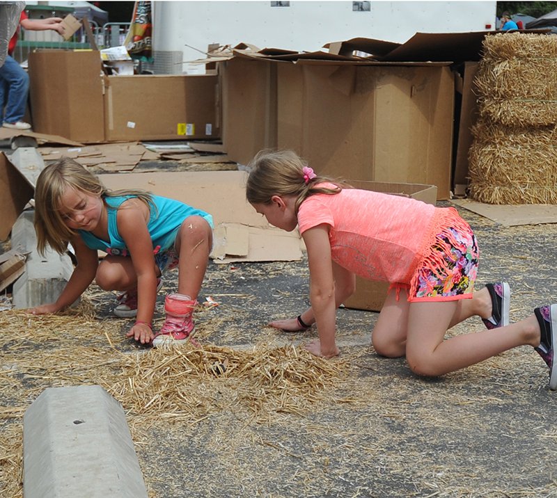 The Sentinel-Record/Mara Kuhn Ali Strawser, 5, left, and Ema Strawser, 9, play in the hay during the 2016 Hot Water Hills Music & Arts Festival at Hill Wheatley Plaza on Saturday, Oct. 1, 2016.