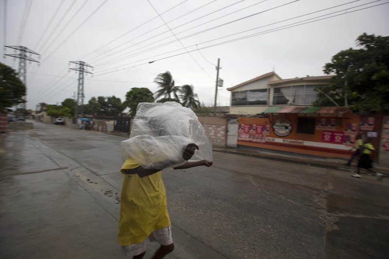 A man crosses a street using a garbage bag as protection from a light rain, in Port-au-Prince, Haiti, Monday, Oct. 3, 2016. Major Hurricane Matthew is slowly churning northward across the Caribbean and meteorologists say the powerful storm is expected to approach Jamaica and southwest Haiti by Monday night. (AP Photo/Dieu Nalio Chery)
