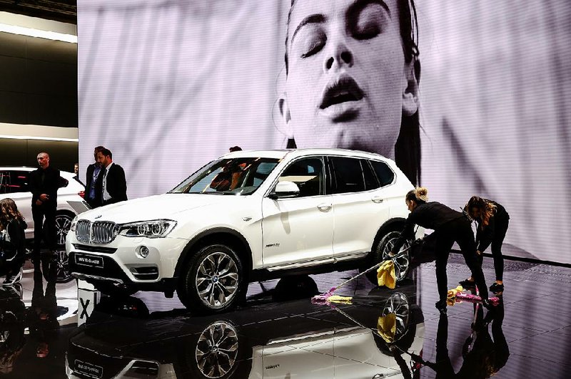 Workers sweep the floor around a BMW X3 sport utility vehicle displayed Friday at the Paris Motor Show at Porte de Versailles exhibition center in Paris. 