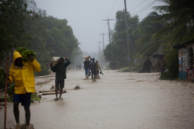 People wade in a flooded street Tuesday as they return to their homes in Leogane in southwestern Haiti after Hurricane Matthew passed through.