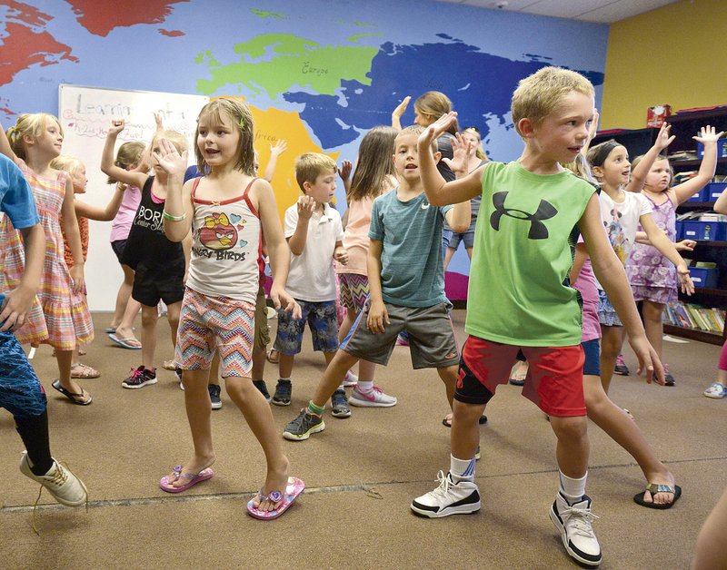 Abigail Tatara of Rogers and Jordan Randolph, both 7, of Bentonville join in an August dance party during a summer Olympics-inspired day of activities at the Carl & Alleen McKinney Unit of the Boys & Girls Club of Benton County in Bentonville. Proceeds from “Sip & Savor” this evening will help the group establish a new teen center in Rogers. 