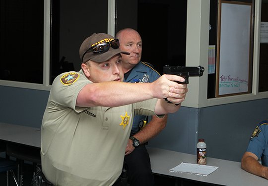 The Sentinel-Record/Richard Rasmussen READY, AIM, FIRE: Arkansas State Police Cpl. James Avant watches Garland County Sheriff's Department Transportation Deputy Jason Whitehead respond Wednesday to an active-shooter scenario on the firearms training simulator at National Park College.