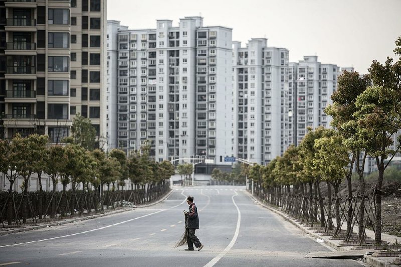 A worker crosses a road in front of residential buildings in the Jiading district of Shanghai in April. Shanghai property values jumped 31 percent in August from a year earlier, government data show. 
