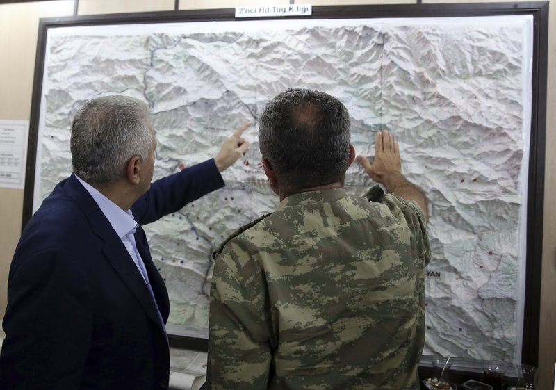 In this Monday, Sept. 5, 2016 photo, an army commander informs Turkey's Prime Minister Binali Yildirim, left, on a Turkey-Iraq border map, in Cukurca, Turkey. 
