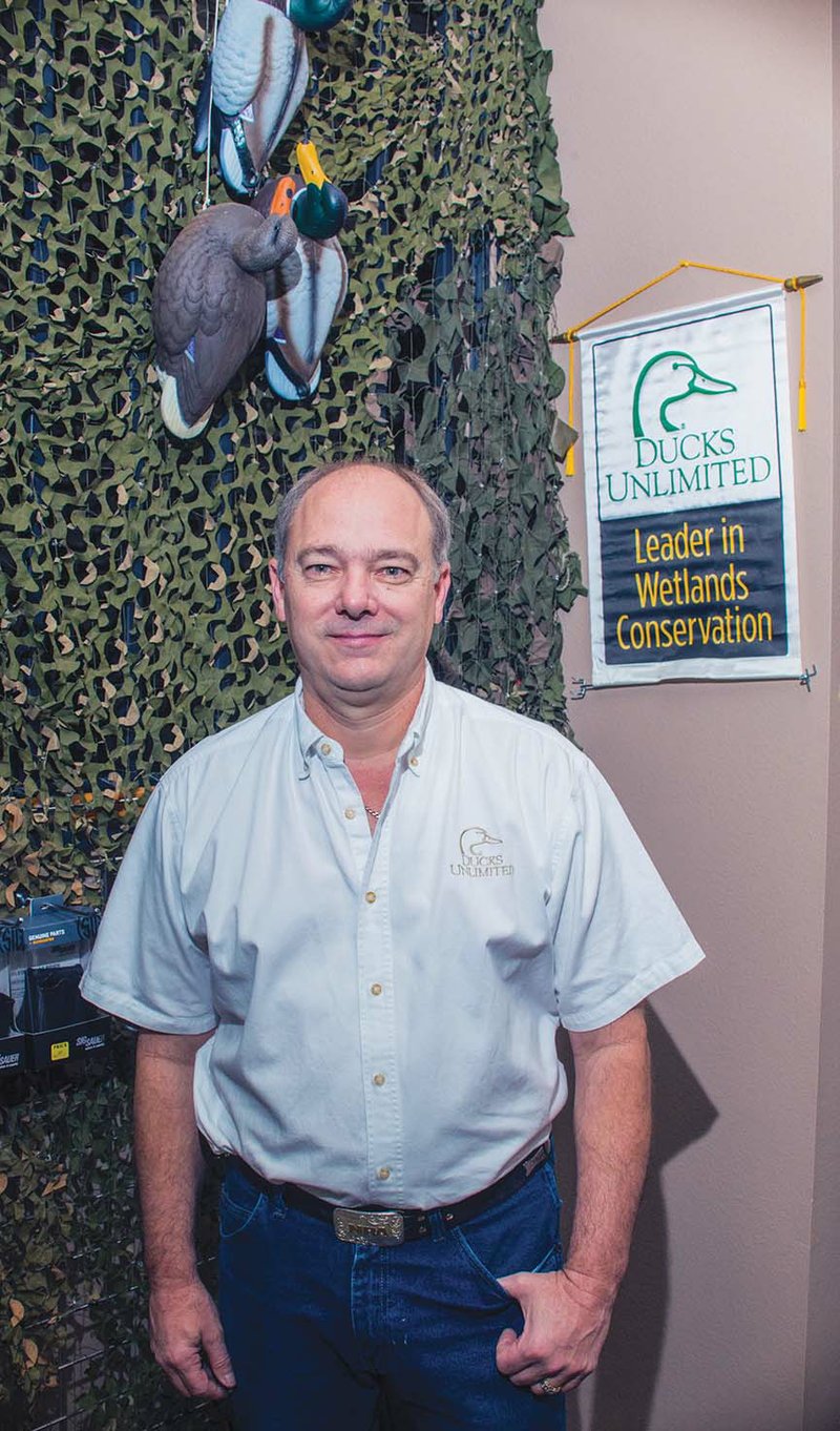 Bryan Hearn of Maumelle, owner of American Tiger Firearms, stands near a Ducks Unlimited banner in his business. He is chairman of the Central Arkansas Chapter of Ducks Unlimited and is in charge of the membership banquet set for Oct. 20 in Little Rock. He said people don’t have to be hunters to join the organization; wetlands conservation is the main objective of the group.