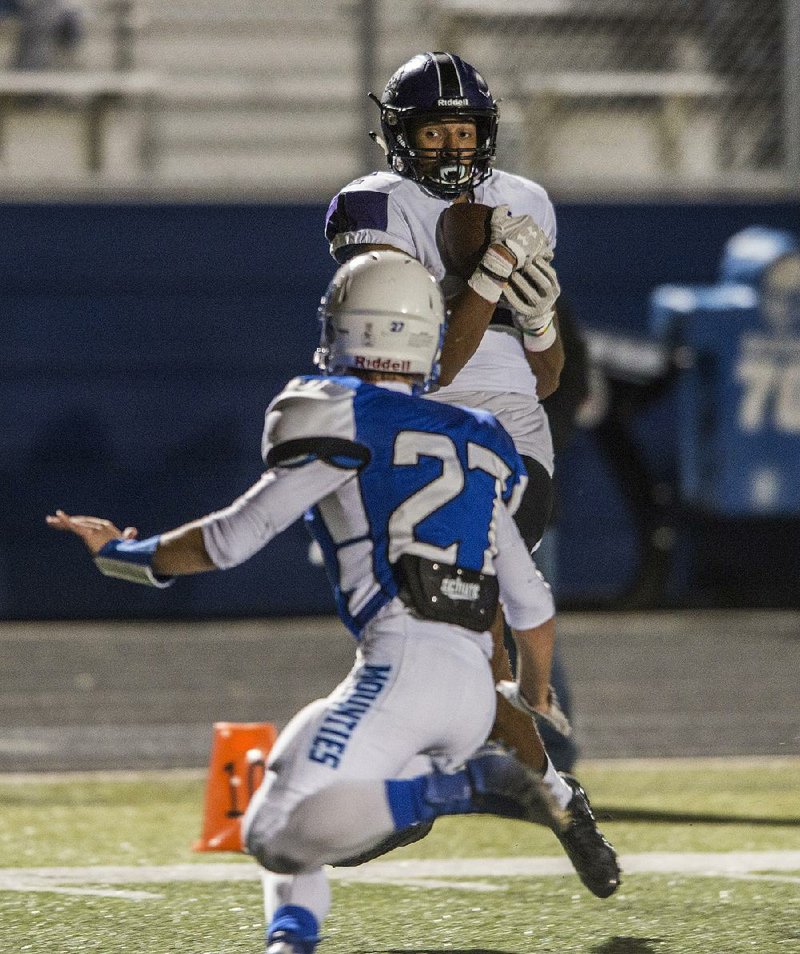 Fayetteville wide receiver Brennon Lewis (back) catches a pass behind Rogers defensive back Landon McClung during the first half. The Bulldogs, ranked No. 5 in Class 7A by the Arkansas Democrat-Gazette, took out the Mounties 54-17.