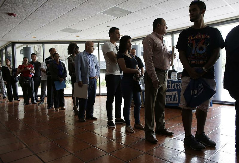 Job seekers line up to register for a career fair in Miami Lakes, Fla., in July. People seeking work led to September’s slight rise in the unemployment rate, the U.S. said Friday.