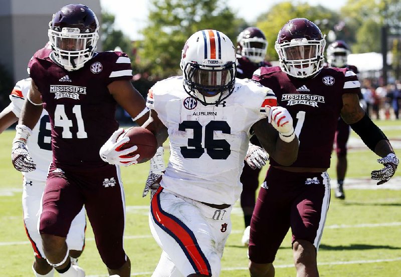 Auburn running back Kamryn Pettway (center) runs past Mississippi State defensive backs Mark McLaurin (left) and Brandon Bryant during the first half of Saturday’s game. Pettway ran for a career-high 169 yards and scored three touchdowns to carry the Tigers past the Bulldogs 38-14.