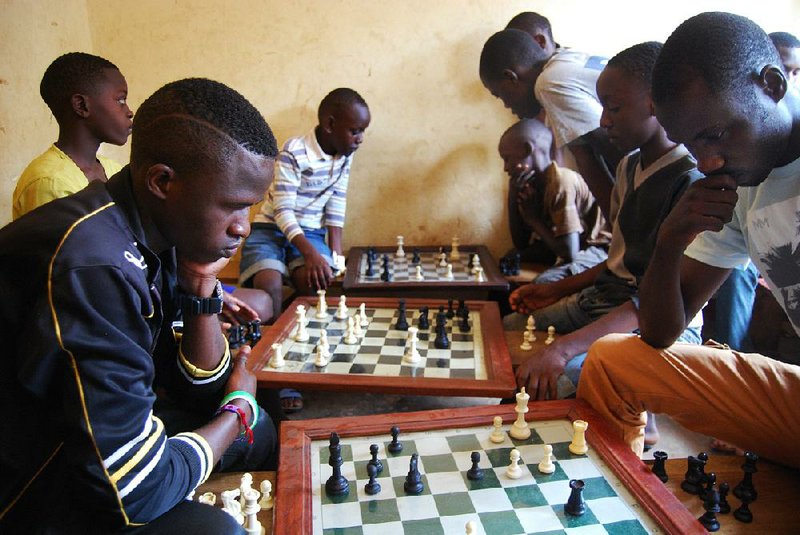 Young players study their moves at the Som Chess Academy in Katwe, Uganda, a Christian mission project founded by Robert Katende, who served porridge along with chess lessons to spur involvement. 