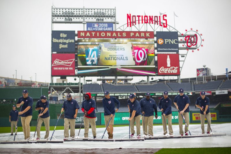 Members of the ground crew clear water off the infield tarp ahead of Game 2 of baseball's National League Division Series between the Los Angeles Dodgers and Washington Nationals at Nationals Park, Saturday, Oct. 8, 2016, in Washington. 