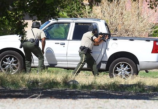 Officers point to a home on Cypress Road after gunshots were fired in Palm Springs, Calif., Saturday, Oct. 8, 2016. Two Palm Springs police officers trying to resolve a family dispute were shot to death when a man they had been speaking calmly with suddenly pulled out a gun and opened fire on them, the city's police chief told reporters. 