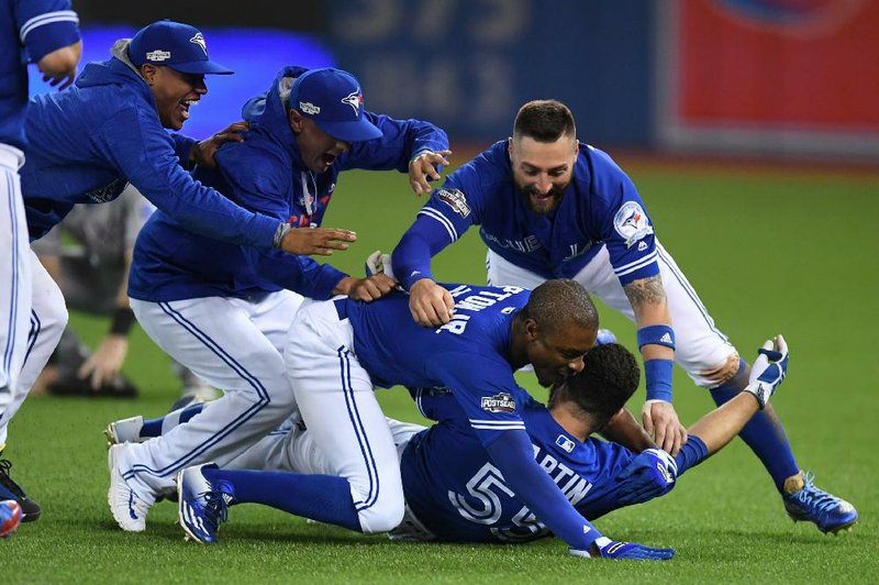 Toronto players celebrate with catcher Russell Martin after his grounder led to the winning run in the bottom of the 10th inning for the Blue Jays who won 7-6 and completed a 3-0 sweep in their American League division series Sunday night.