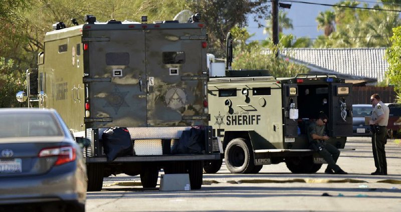 Riverside County sheriff’s deputies wait in front of a house in Palm Springs, Calif., where a suspect in the shooting of three Palm Springs police officers was apprehended Sunday