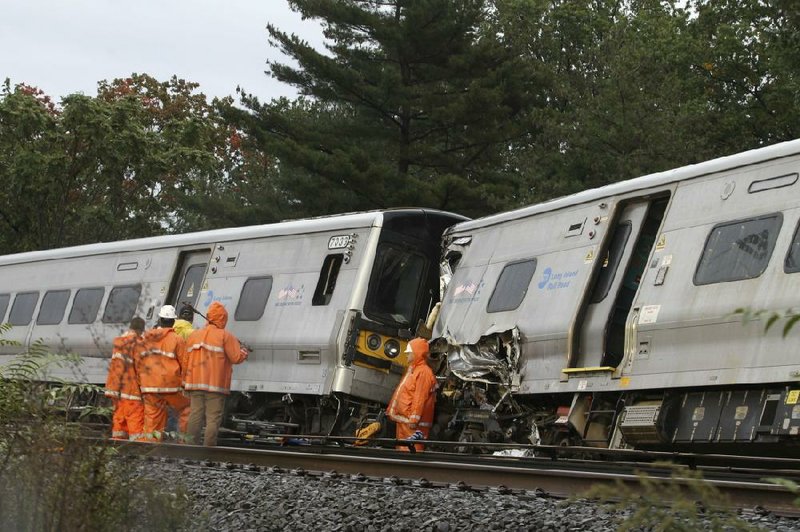 Investigators and workers survey the scene Sunday where an eastbound Long Island Rail Road commuter train derailed after striking a work train in New Hyde Park, N.Y., on Saturday night.