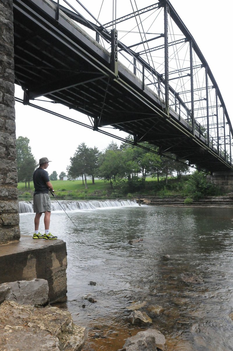 Nick Hamilton of North Little Rock fishes July 6 below the War Eagle Bridge. The original six-month schedule to renovate the bridge has been pushed back about a month with delays in the approval process with state and federal agencies.