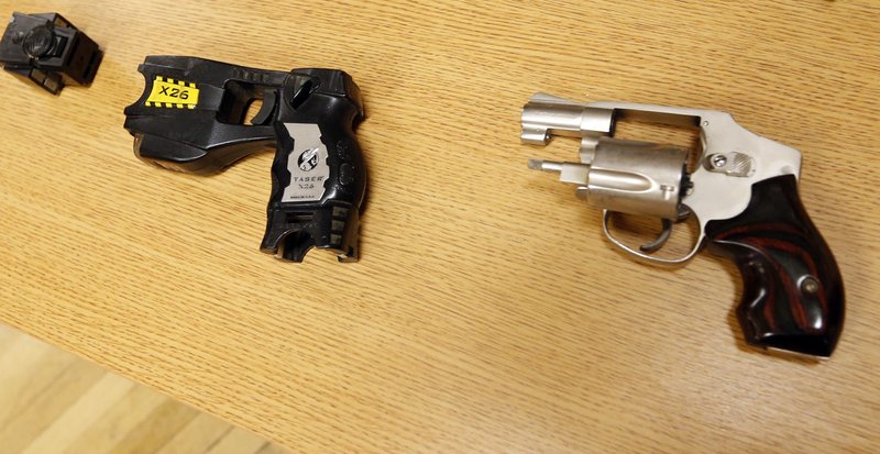 In this April 10, 2015, file photo, a Taser and handgun are displayed in Tulsa, Okla. In the recent shootings of unarmed black men in a San Diego suburb and in Tulsa, Oklahoma, the police officers who fired the fatal shots were accompanied by officers who simultaneously drew their stun guns. 