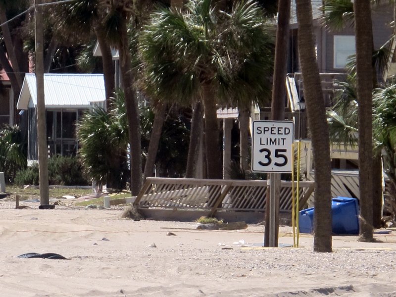 Debris from the storm surge of Hurricane Matthew litters the ocean front street in Edisto Beach, S.C., on Monday, Oct. 10, 2016. The speed limit sign shows the depth of sand pushed up by the surge. Town officials say the storm washed between 3 and 4 feet of sand onto the street and the community took its worst hurricane hit since Hurricane David back in 1979. (AP Photo/Bruce Smith)
