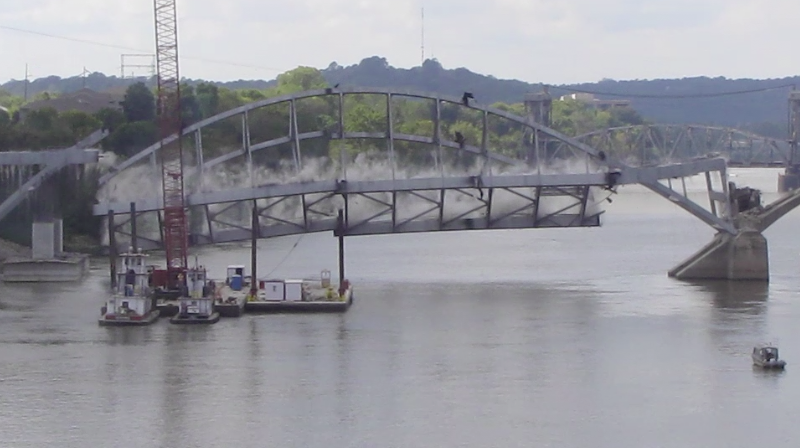 The Broadway Bridge arch falls into the Arkansas River after it was tugged down by cables attached to a barge Tuesday afternoon.