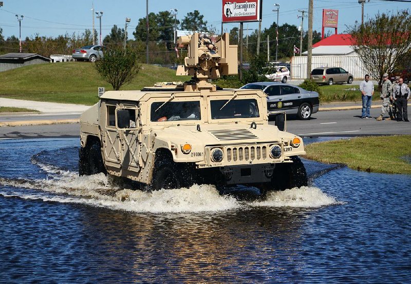 A North Carolina National Guard vehicle drives along a state highway in Kinston, N.C., on Tuesday as floodwaters overtake the road. 