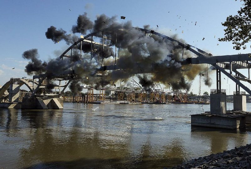 Explosive charges go off across the Broadway Bridge’s steel arch Tuesday morning. The charges were supposed to drop the bridge into the Arkansas River, but it held on, barely teetering. 