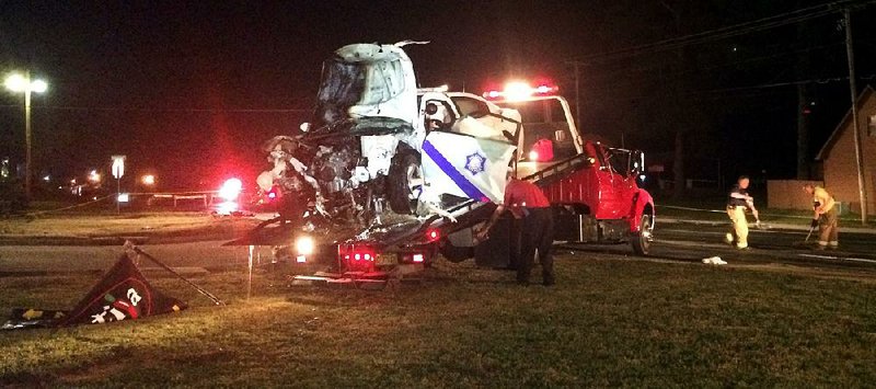 An employee of Holcomb’s Recovery loads the wreckage of an Arkansas State Police patrol car after a crash in Hot Springs.  