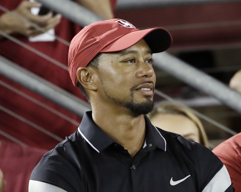In this Oct. 8, 2016, file photo, golfer Tiger Woods, left, watches an NCAA college football game between Stanford and Washington State, in Stanford, Calif. 