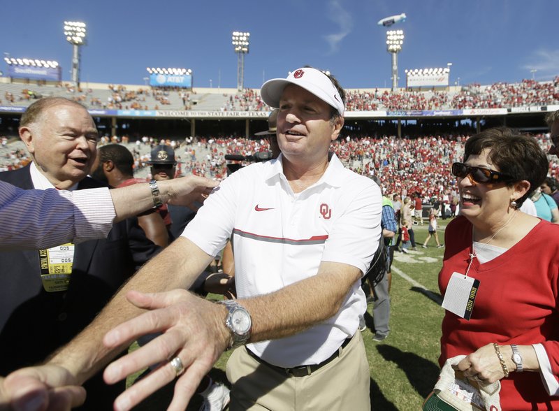 Oklahoma head coach Bob Stoops, center, is congratulated after their 45-40 win over Texas in an NCAA college football game in Dallas Saturday, Oct. 8, 2016. 