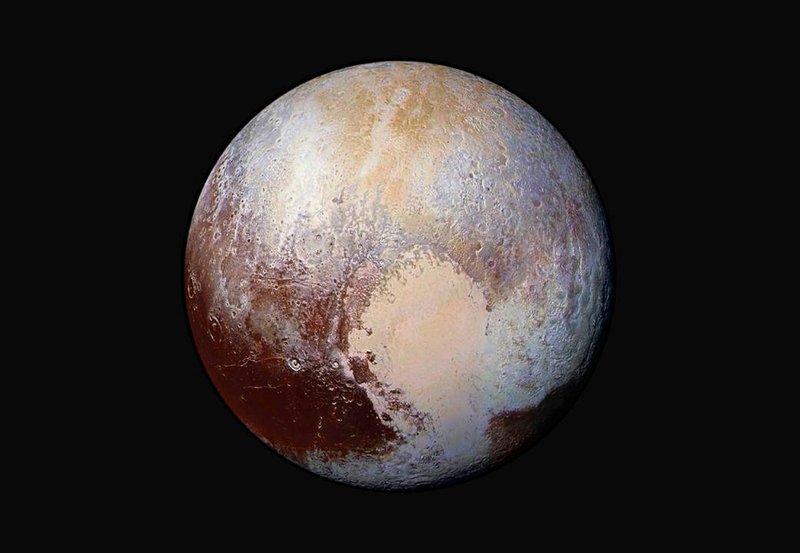 An exaggerated color photo shows the varied terrain of Pluto, the most well-known dwarf planet.