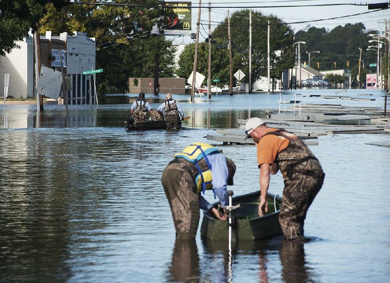 City workers use boats Wednesday to travel down a street in Lumberton, N.C., to the municipal water treatment plant through floodwaters caused by rain from Hurricane Matthew. 