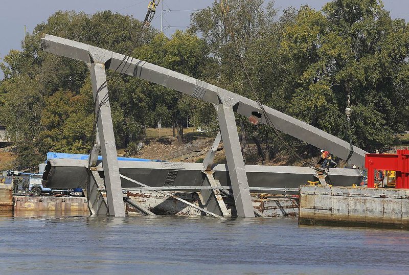 Another crew works to pull another piece of the arch to dry land as efforts went past a 24-hour permit that closed part of the river to barge traffic. The arch, which withstood explosive charges Tuesday that were supposed to drop it into the river in an upright position, had to be pulled down. It settled on its side, making the retrieval work more difficult and dangerous. 