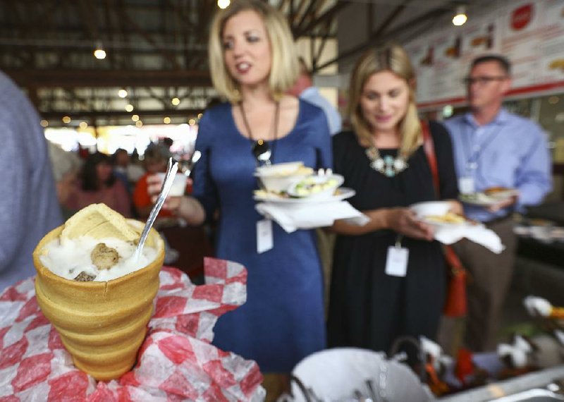 Media representatives line up Wednesday to sample the Conewich (sausage, pulled pork and gravy in a baked bread cone) at a preview of the food offerings for the Arkansas State Fair, which starts Friday.