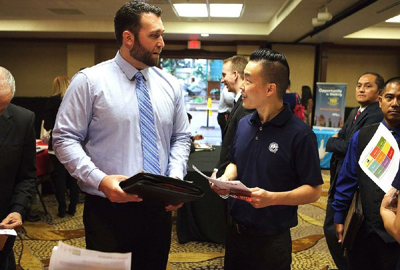 A Panda Restaurant Group Inc. recruiter (right) speaks with a job seeker at a job fair in Santa Ana, Calif., on Oct. 6. The number of Americans claiming unemployment benefits held steady last week, the Labor Department said Thursday.