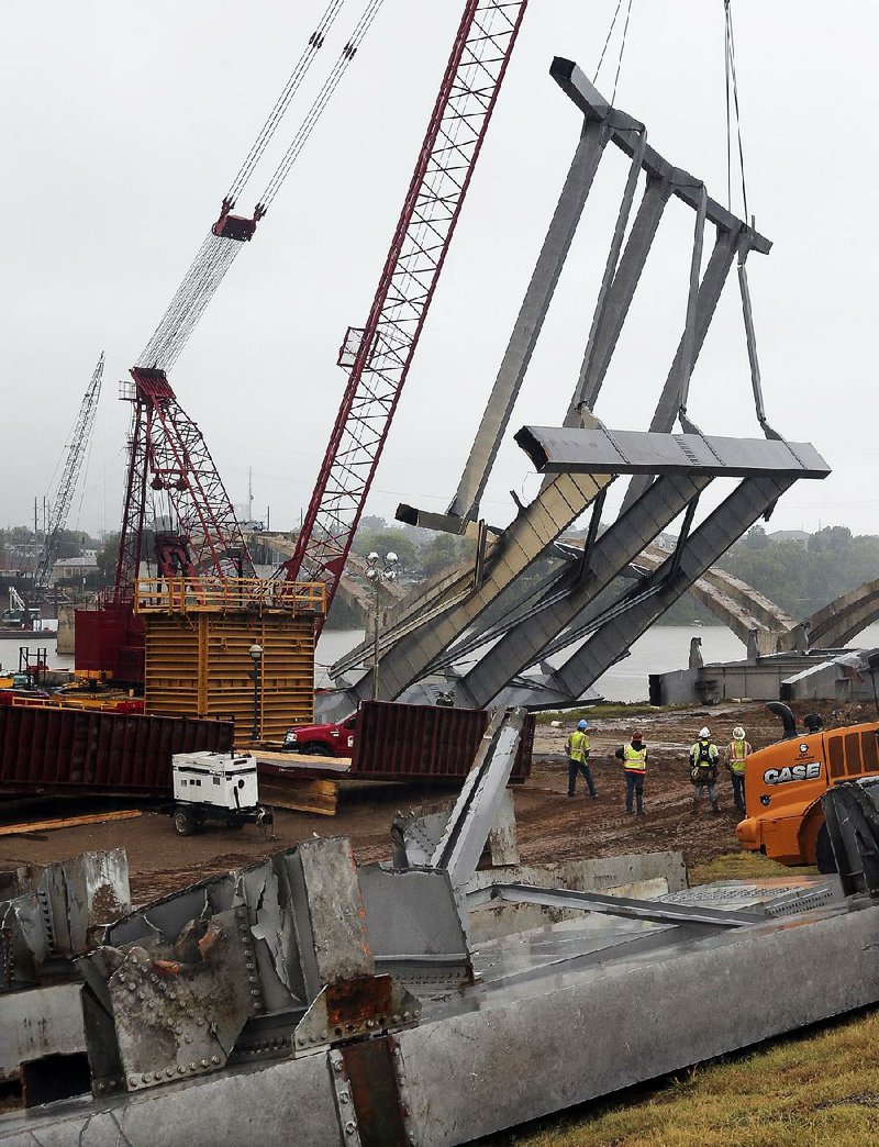 Workers watch as a crane removes the last two steel arch sections of the Broadway Bridge from the Arkansas River Thursday morning after it was take down Tuesday. The job took 48 hours to complete, despite a 24-hour deadline given by the Corps of Engineers to have the pieces cleared from the Arkansas River’s navigation channel.