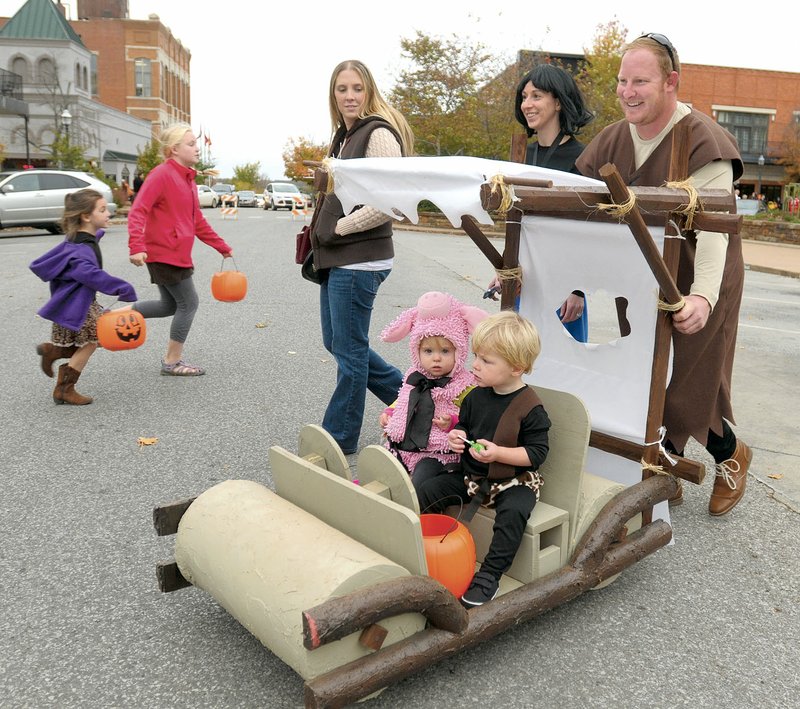 Jarred Ellis, right, and his wife, Jenny, of Fayetteville walk with friend, Cassie Taylor of Springdale as they push their son, Sawyer, and 17-month-old friend, Karsyn Tolley at the 2015 Trick or Treat on the Square in Fayetteville.