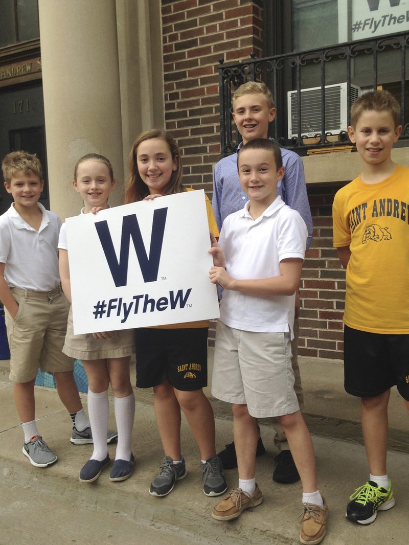 In this Oct. 6, 2016 photo, from left, Sean Leahy, Kaitlin Reap, Addison Casavechia, Connor Burns, blue shirt, Quinn Roberts and Max Oldham, students at Hawthorne Elementary School near Wrigley Field in Chicago, hold a Cubs W sign outside the school.